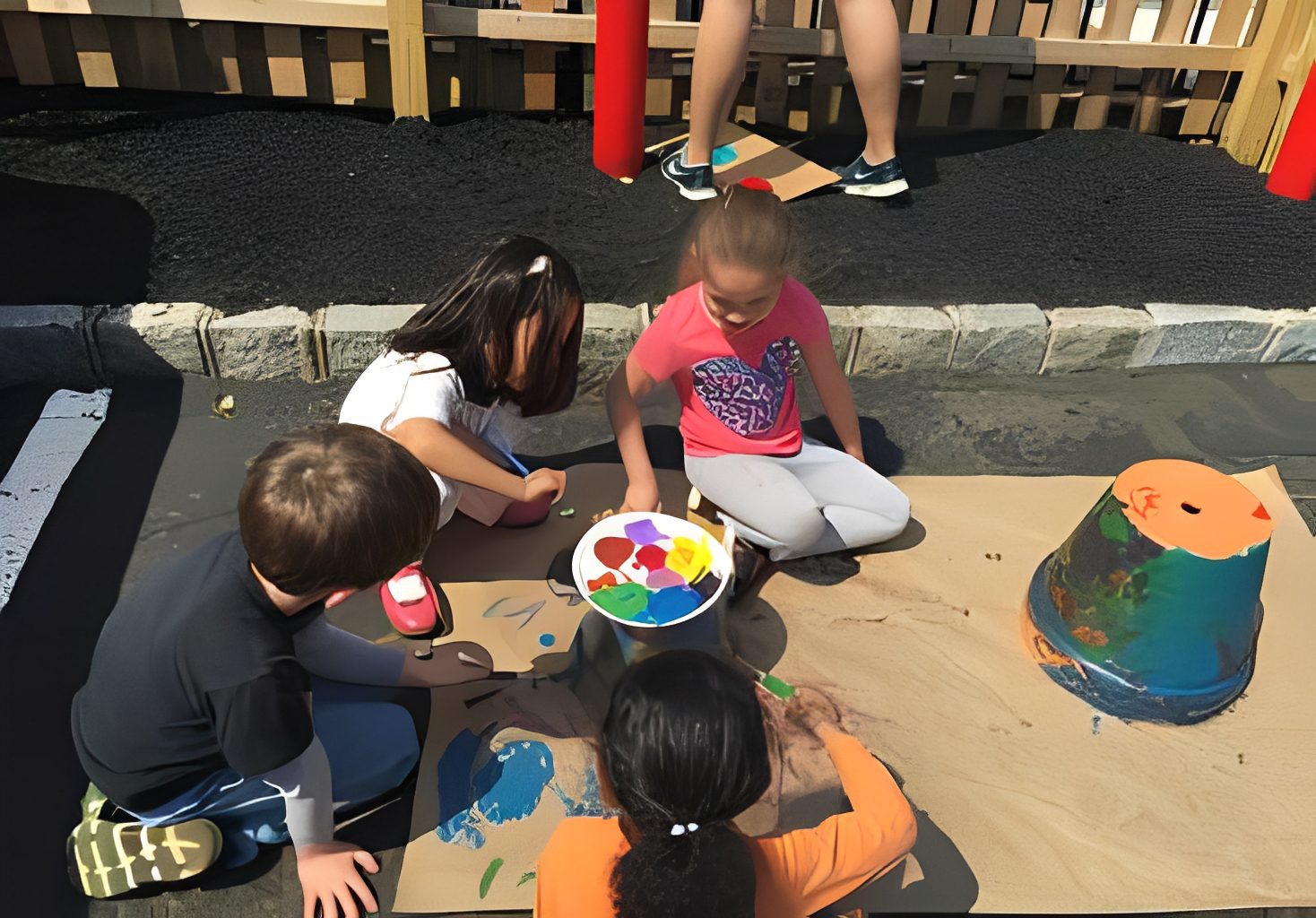Children painting outside with colorful paints.
