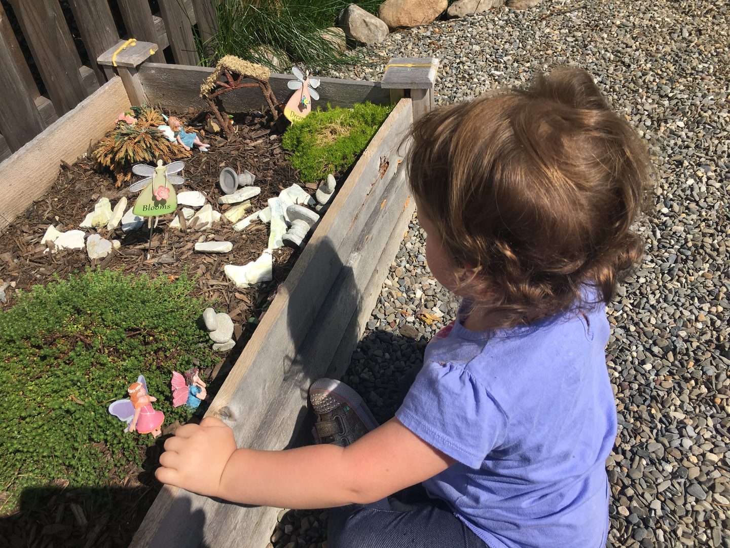 Child exploring a small garden with decorations.