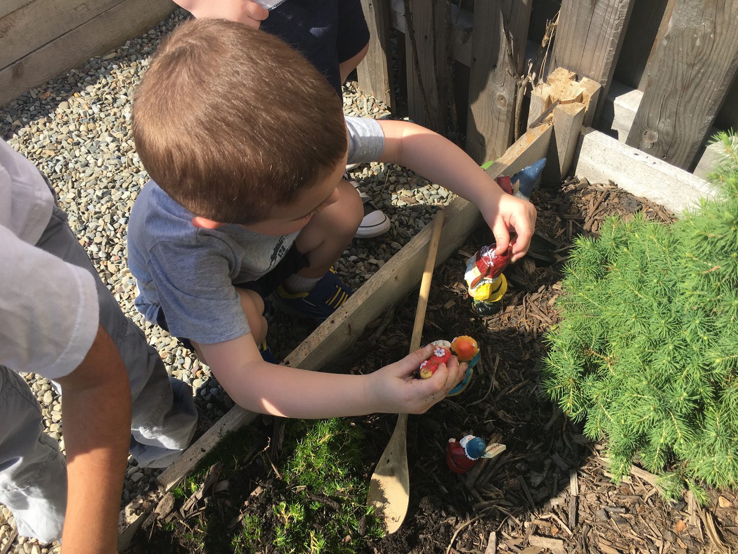 Child playing with toys in garden setting.